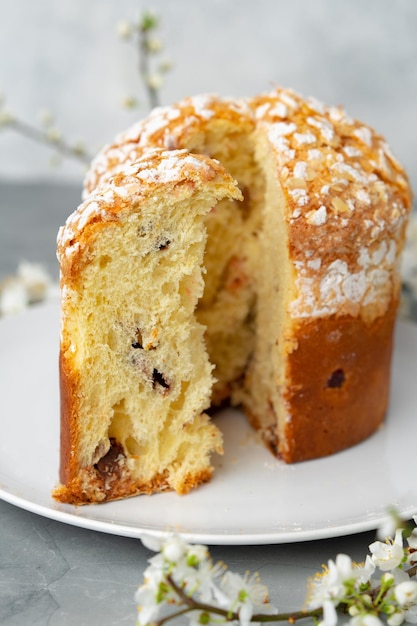 Cortar el pastel de pascua en un plato decorado con ramas de flores de primavera