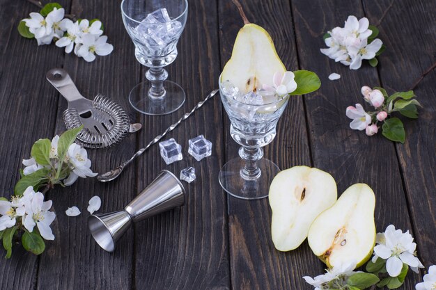 cortar peras, vasos, hielo, artículos para hacer un cóctel en un bar y flores de pera