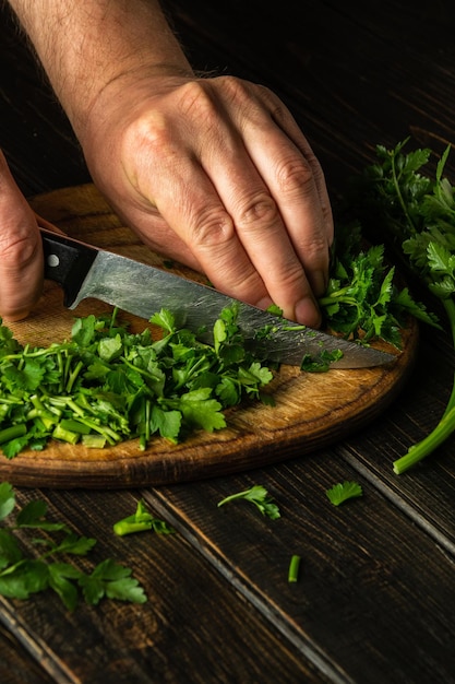 Cortar perejil verde en una tabla de cortar con un cuchillo para cocinar comida vegetariana Comida campesina