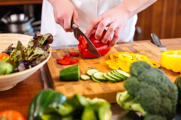 Cortar pimiento rojo para ensalada en mesa de madera