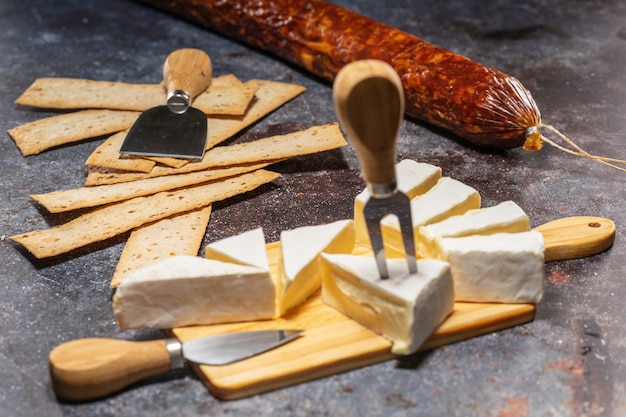 Foto cortar el queso brie acostado sobre una tabla de cortar