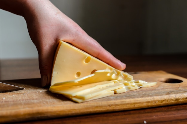 Foto cortar el queso en una tabla de madera.