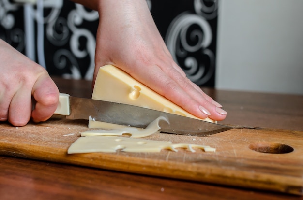 Foto cortar el queso en una tabla de madera.