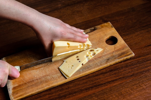 Cortar el queso en una tabla de madera.