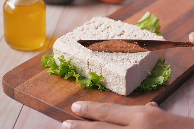 Cortar rebanadas de tofu en una tabla de cortar en la mesa