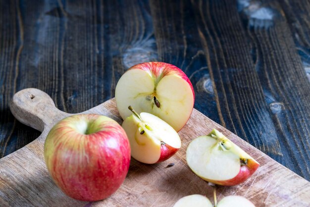 Cortar una tabla vieja con trozos de manzana roja madura