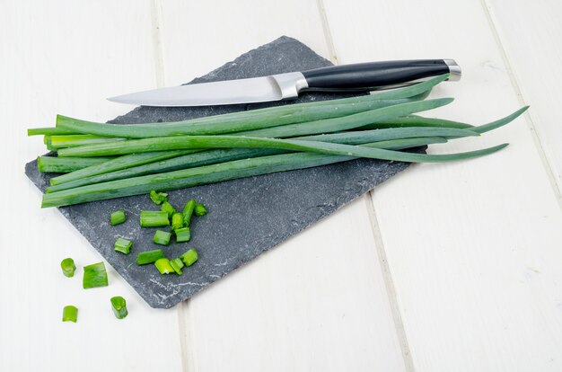 Foto cortar tallos de cebollas verdes, un ingrediente en la cocina