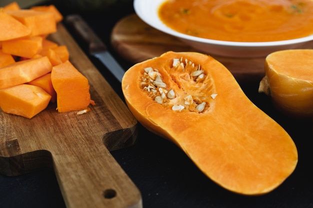 Cortar trozos de calabaza cruda sobre la tabla de cortar de madera en la mesa