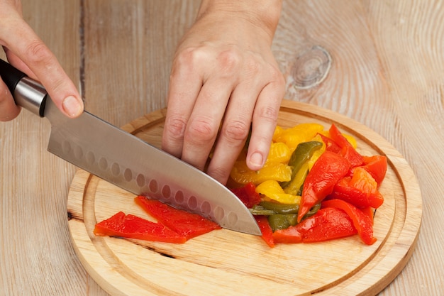 Foto cortar las verduras con un cuchillo de cocina en el tablero