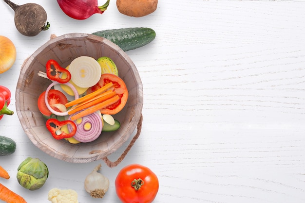 Cortar verduras frescas en un viejo cubo de madera Copiar espacio en una mesa de madera blanca al lado