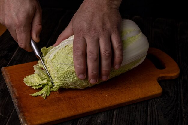 Cortar verduras Las manos del hombre cortando repollo en una tabla de cortar