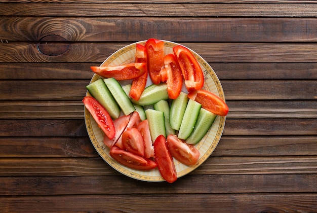 Cortar verduras - tomate, pimiento, pepino en una tabla de madera