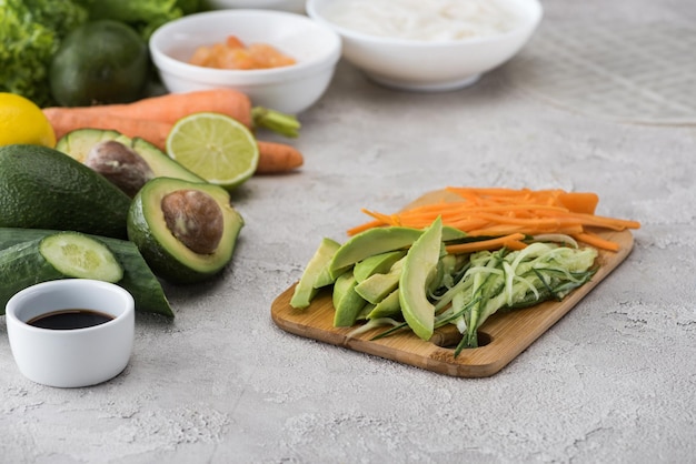 Cortar la zanahoria y el pepino aguacate en la tabla de cortar entre los ingredientes crudos