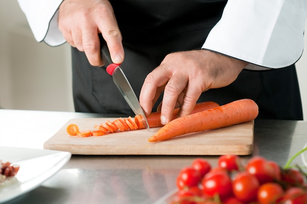 Cortar la zanahoria sobre una tabla de madera para la preparación de comidas en el restaurante