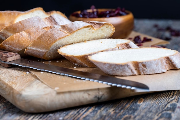 Corte a baguete de trigo fresco em vários pedaços fatiados de baguete fresca e macia em uma tábua e mesa de corte