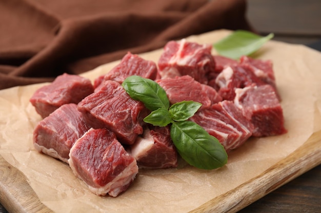 Corte a carne fresca com folhas de manjericão na placa de madeira fechada