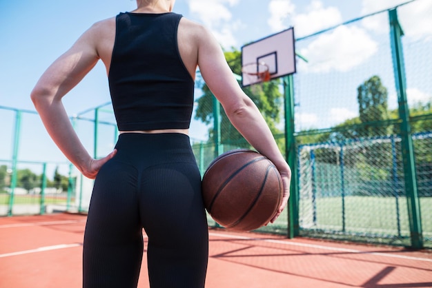 Corte a foto de um jogador de basquete atlético segurando uma bola na mão em um campo de basquete Jogo de basquete lazer estêncil ao ar livre