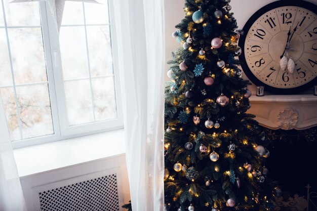 Corte a vista de uma árvore de Natal lindamente decorada no canto da sala na janela