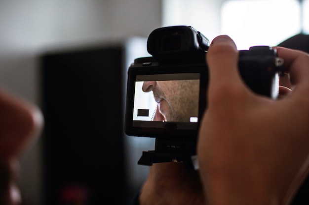 Corte a vista e close-up das mãos do cinegrafista ajustando a câmera. Gravar vídeo ou tirar foto do rosto de um jovem ocupado.