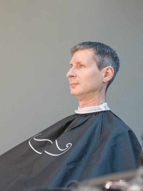 Corte de cabello masculino en un salón de belleza. Hombre en silla de barbero, peluquero corte de pelo. Barbería.