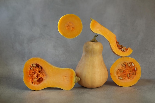 corte la calabaza fresca en el fondo gris