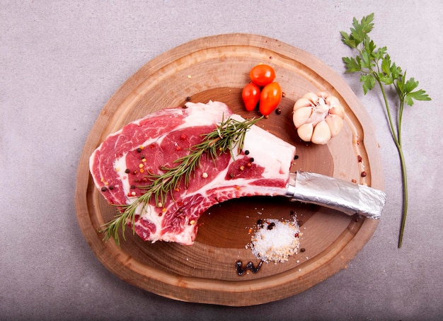 Corte la carne de costilla cruda de mármol en la vista superior de la esquina en totora con ajo, sal gruesa, pimienta y romero