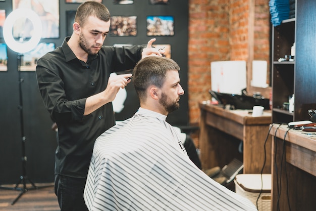 Corte de cabelo no cabeleireiro. barbeiro corta o cabelo na cabeça do cliente