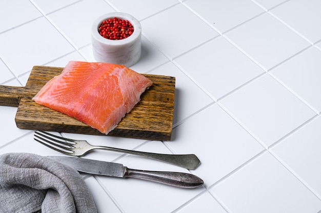 Corte de filé de salmão fresco em fundo de mesa de azulejos quadrados de cerâmica branca com espaço de cópia para texto