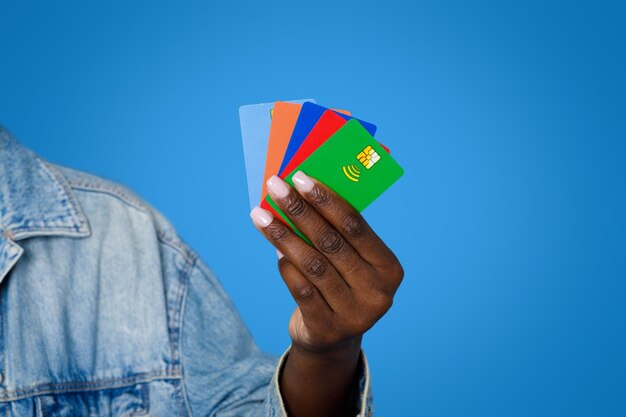 Foto corte de mulher negra segurando vários cartões bancários coloridos