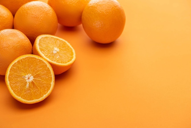 Corte delicioso maduro y naranjas enteras sobre fondo colorido