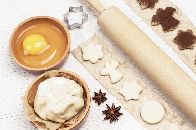 Corte em forma de biscoitos por molde polvilhado com chocolate no papel. ovos, massa de pão, paus de canela e rolo. vista do topo.