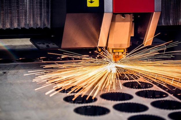 Foto corte láser cnc de metal, tecnología industrial moderna. pequeña profundidad de campo. advertencia: disparos auténticos en condiciones difíciles. un poco de grano y tal vez borrosa.