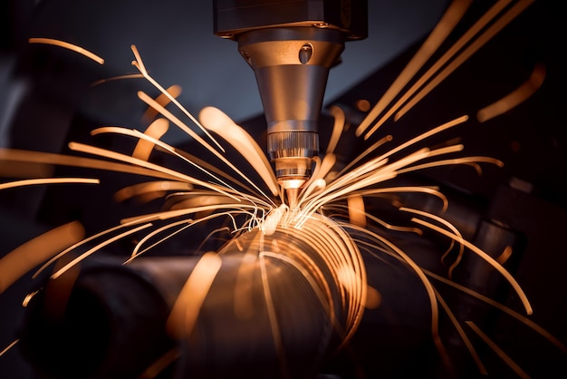 Foto corte láser cnc de metal, tecnología industrial moderna realización de detalles industriales. la óptica láser y el cnc (control numérico por computadora) se utilizan para dirigir el material o el rayo láser generado.