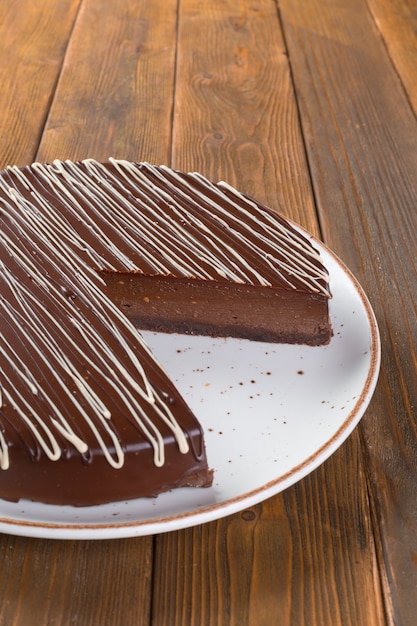 Foto corte o bolo de chocolate no prato na mesa de madeira de perto