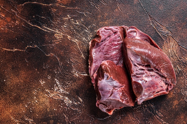 Corte o coração cru de carne ou vitela em uma mesa de açougueiro. Vista do topo.