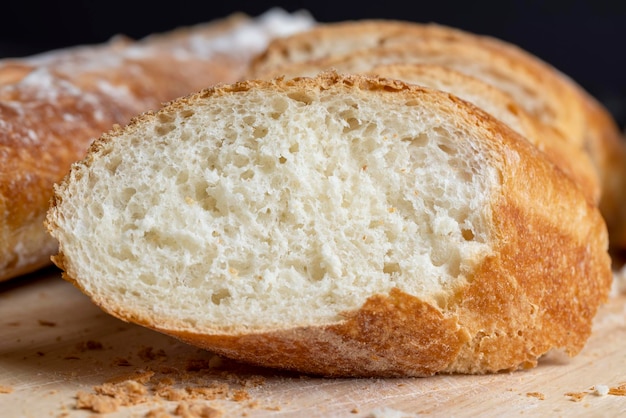 Corte o pão branco em pedaços de baguete branca tradicional com polpa porosa