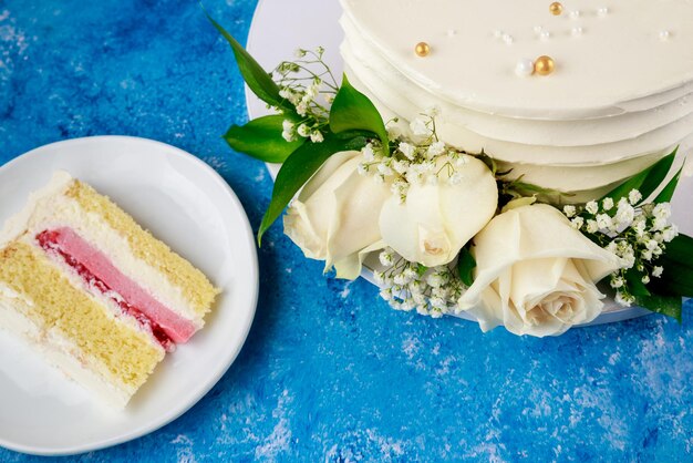 Corte el pastel de bodas de fresa con rosas blancas.