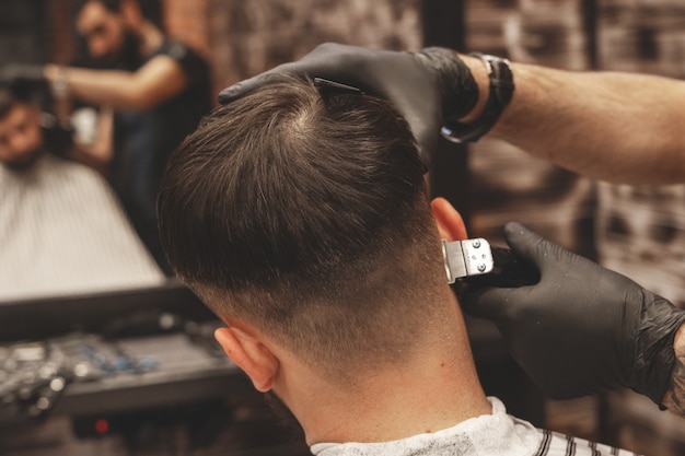 Corte de pelo en la barbería. Peluquero corta el pelo en la cabeza del cliente