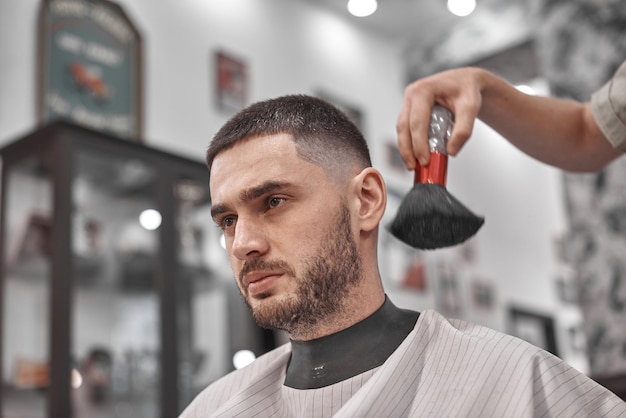 Corte de pelo y peinado en peluquería. Cuidado del cabello. Estilo y estilo de vida de los hombres. Barber trae un corte de pelo y barba a su cliente.