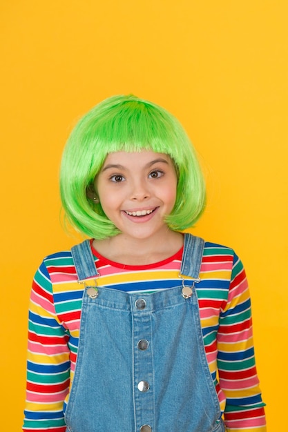 Corte de pelo de peluca que es fácil de manejar Niña feliz usar peluca de pelo verde fondo amarillo Sonrisa de niña con peinado de peluca corta Peluca elegante o cabello postizo Moda y belleza Salón de belleza