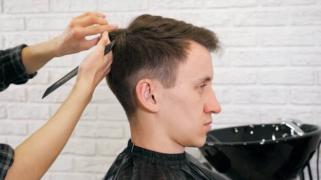 Corte de pelo de peluquería femenina haciendo peinado masculino.