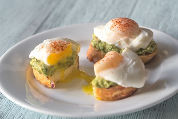 Corte el sándwich con guacamole y huevo escalfado