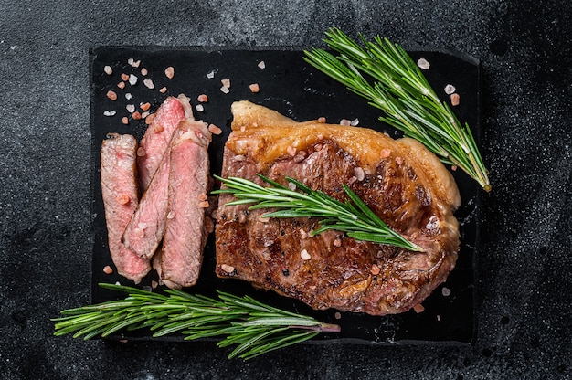 Corte um bife de carne de boi de Nova York assado ou striploin em uma placa de mármore