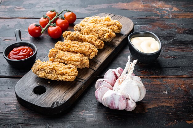 Cortes de alitas de pollo empanizadas sobre fondo de madera oscura.