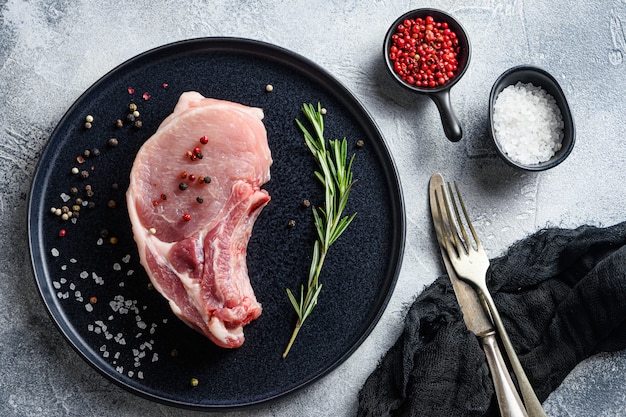 Cortes de carne cruda en un plato, con hierbas y especias.