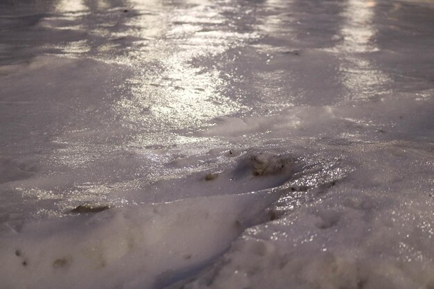 La corteza de hielo reluciente con reflejos de luz que cubren la fría nieve blanca por la noche