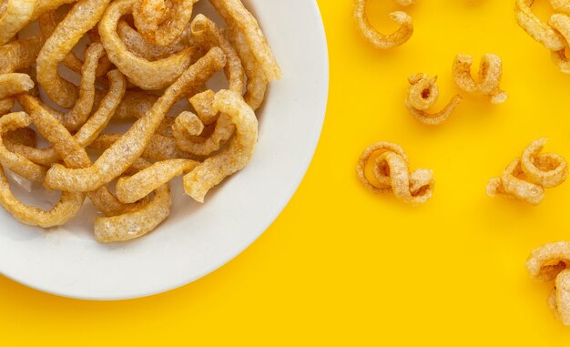 Foto cortezas de cerdo crujientes fritas sobre fondo amarillo.