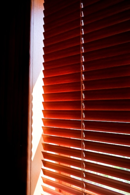 Cortinas plásticas alaranjadas fechados com luz solar na manhã. janela com persianas. design de interiores de sala de estar com cortinas horizontais de janela. janela com venezianas de proteção solar