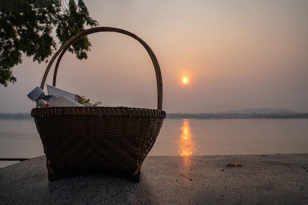 Las cosas en una cesta de mimbre para ofrecer comida o dar limosnas a los monjes en una silla de piedra junto al río Mekong Tailandia al amanecer