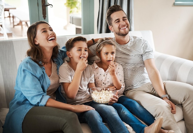 Las cosas más simples de la vida ofrecen el mayor placer Foto de una joven familia feliz relajándose en el sofá y viendo la televisión juntos en casa